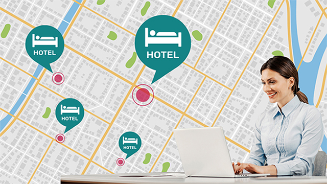 A woman sitting at the desk is using her laptop to manage hotel TVs across different locations.